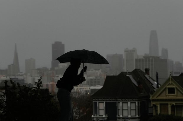 Pedestrian with an umbrella at Alamo Square Park in San Francisco during the winter storm, Dec. 23, 2025.