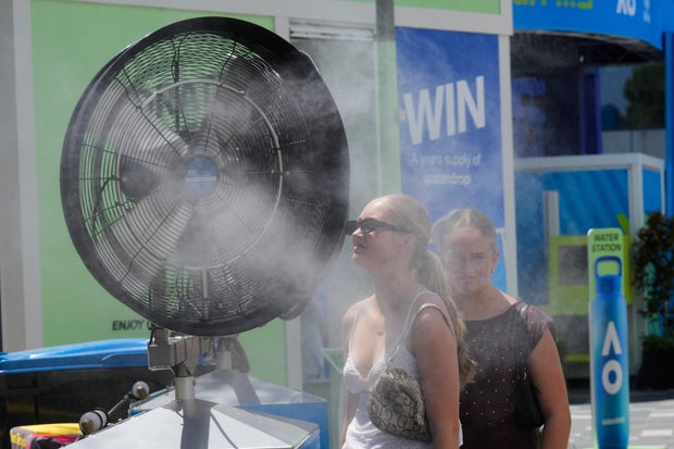 Fans cool down in front of water misters at the Australian Open in Melbourne during extreme heat on Jan. 27, 2026.