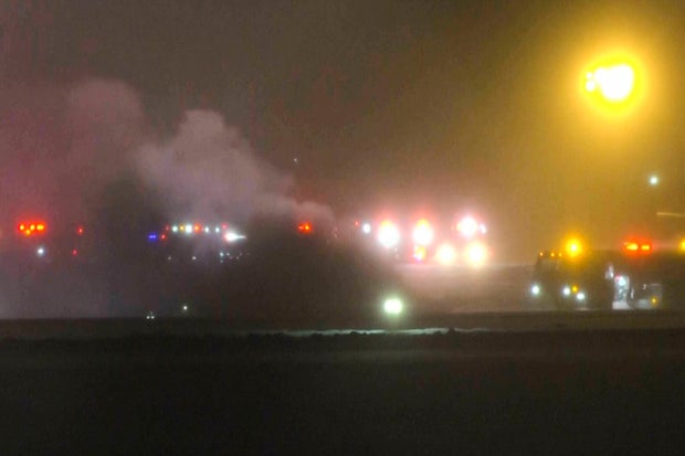Emergency crews at the scene of the Bangor International Airport business jet crash during snowfall