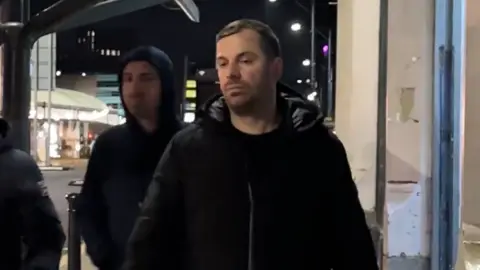 Roland Reka (left) and Florjan Reka (right) walking past a bus stop in Manchester.