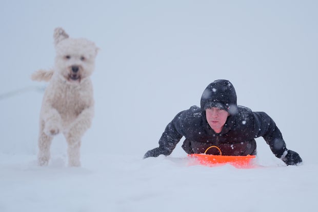 Charlotte, North Carolina, blanketed in snow as a resident sleds with his dog.