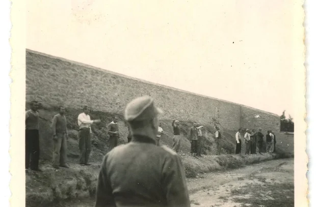 Archival WWII photo depicting men lined against a wall under guard at the Kaisariani shooting range in Athens, 1944; from the recovered collection now held by the Greek state.