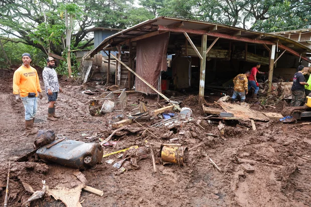 Residents and volunteers clean up flood damage in the Otake Camp community of Waialua, Oahu, after the Kona Low storm on March 22, 2026. (Marco Garcia/AFP via Getty Images)
