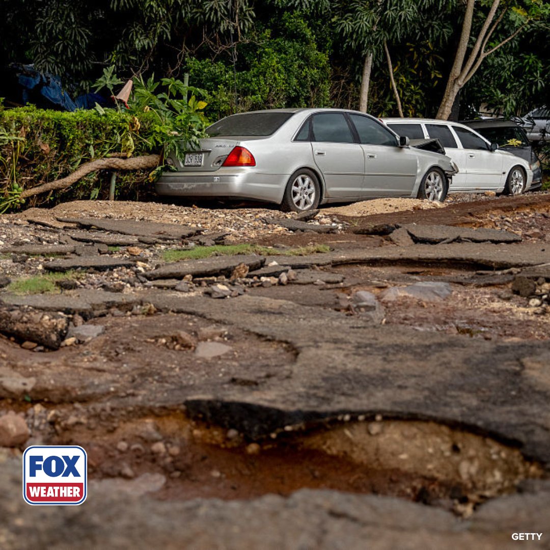 Washed-out road and damaged vehicles following severe flooding on O'ahu.