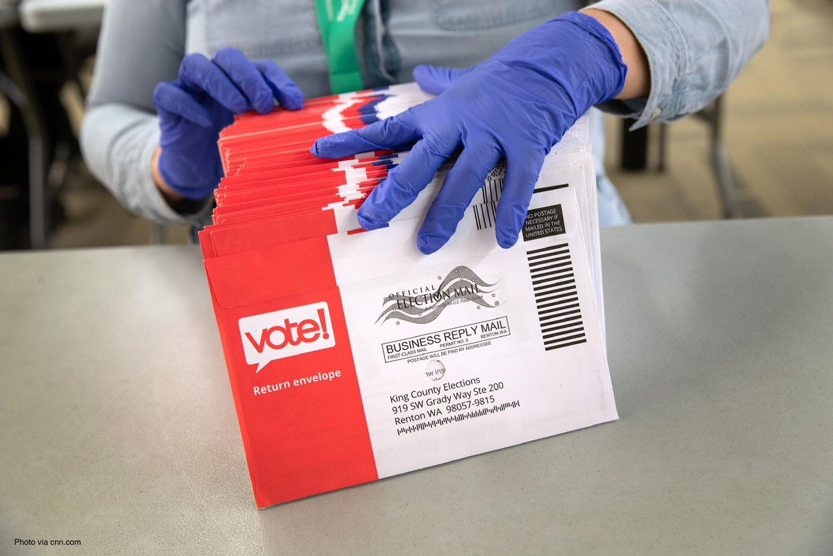 Workers sort and stack mail-in ballot envelopes in trays.