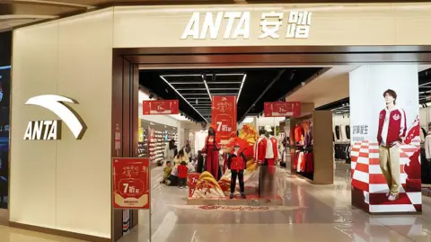Front entrance of an Anta shop in China with red discount banners