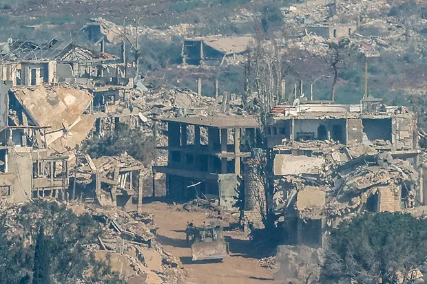 Israeli military vehicle drives along a road past destroyed houses in southern Lebanon near the Israel border on April 27, 2026.