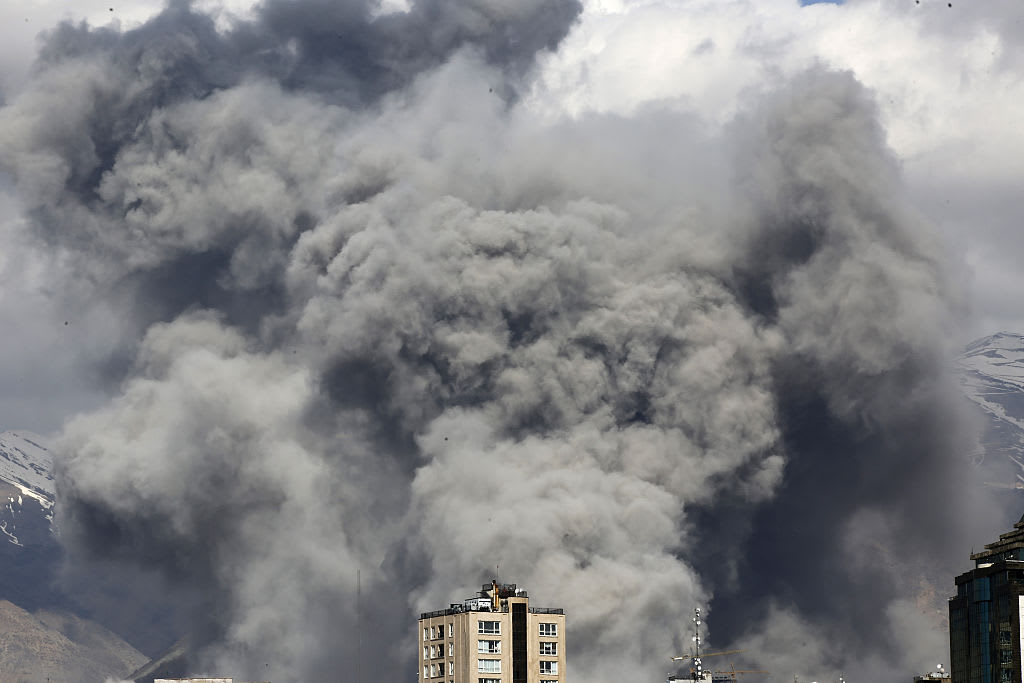 A massive smoke cloud rises above a city skyline amid the ongoing Iran conflict.