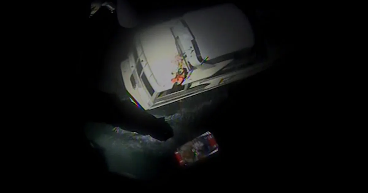 Aerial view of a small vessel and rescue equipment on dark water during a nighttime search; illustrative image