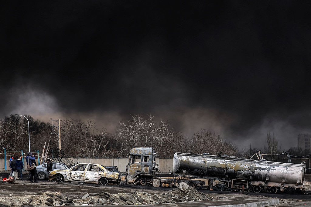 Burned fuel trucks and cars with thick smoke after a strike, illustrating damage to energy transport