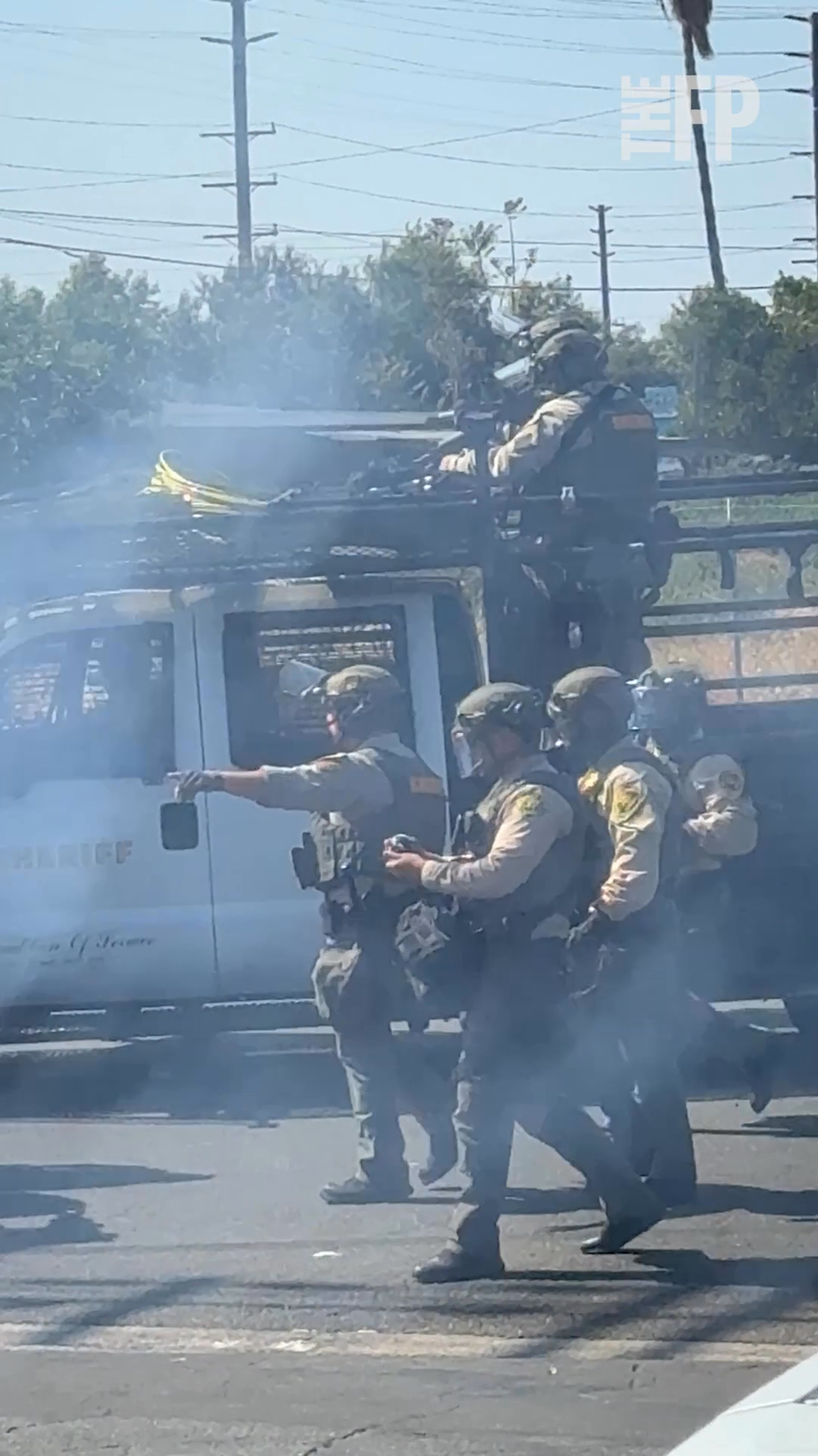 Law enforcement officers in tactical gear amid smoke during a protest response.
