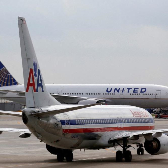 FILE PHOTO: A United Airlines airplane passes by an American Airlines plane at O'Hare Airport in Chicago - Jim Young/Reuters